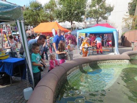 Viel los am Schlossbrunnen: Kinder steuern ferngesteuerte Schiffsmodelle im Wasser bei einem Fest.