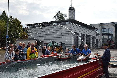 Tag der Offenen Tür bei der Feuerwehr Pirmasens mit Modellschiffen im Wasser und begeisterten Zuschauern.