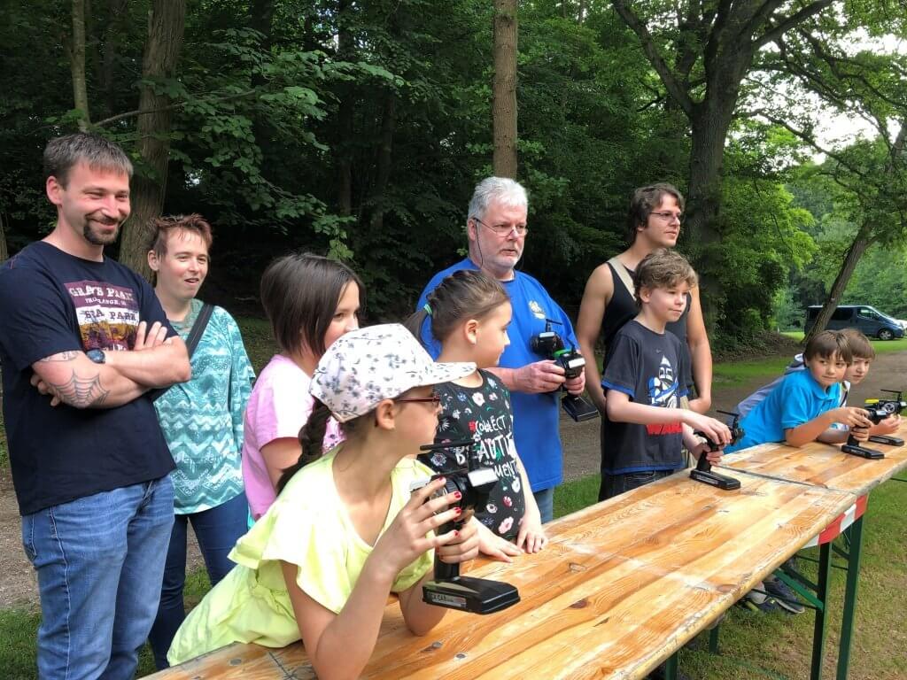 Gruppenevent mit Kindern und Erwachsenen, die ferngesteuerte Schiffsmodelle steuern. Spaß und Teamarbeit im Freien.