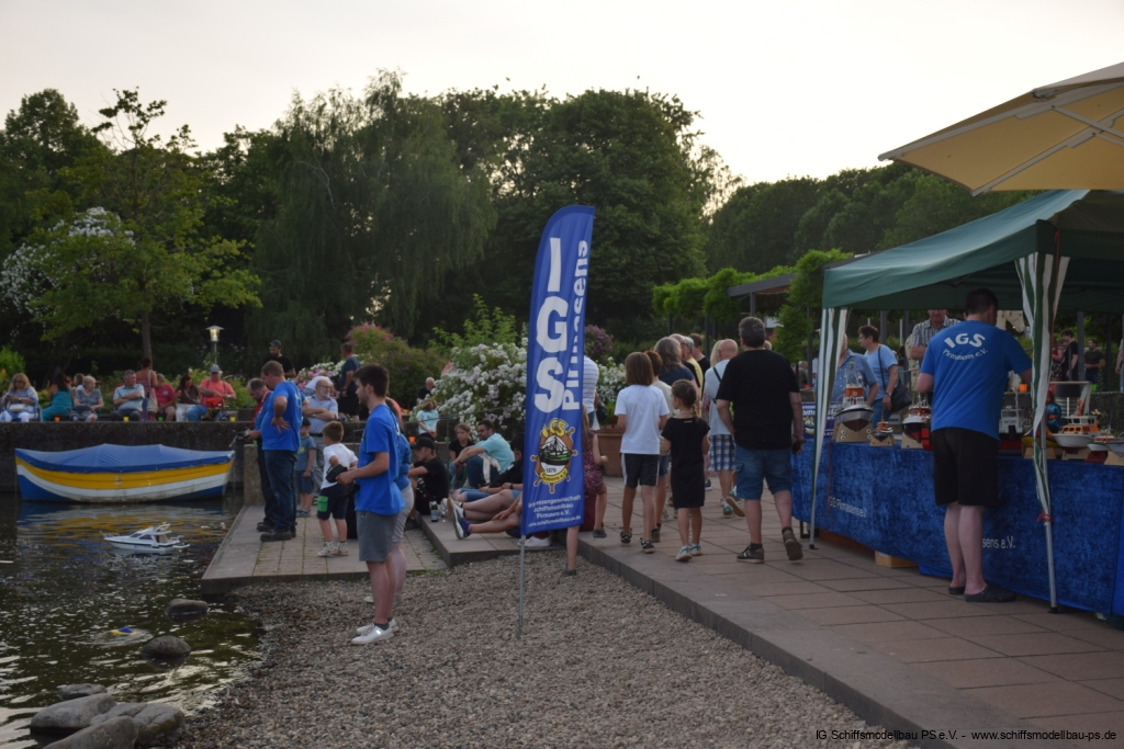 Besucher genießen ein Schiffsmodell-Event am Wasser, mit Modellen und Ständen im Hintergrund.