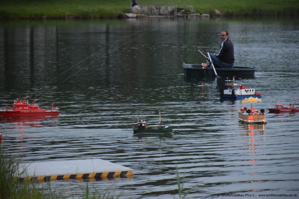 Ein Modellbauer steuert mehrere ferngesteuerte Schiffsmodelle auf einem ruhigen Gewässer in Pirmasens.