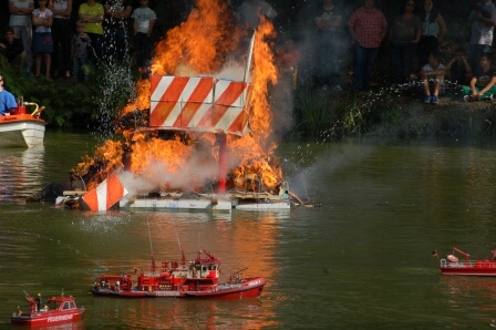 Modellfeuerwehrboote löschen ein brennendes Schiff auf einem Gewässer während einer Vorführung in Pirmasens.
