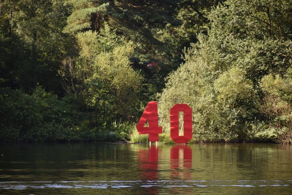 Rote Zahl 40 spiegelt sich im Wasser, umgeben von grüner Natur, ideal für Schiffsmodellbau-Events.