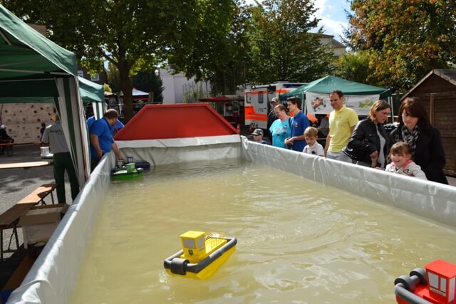 Besucher beobachten ferngesteuerte Schiffsmodelle in einem Wasserbecken bei einer Veranstaltung in Pirmasens.